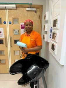 Volunteer Momica stands holding a hairdryer