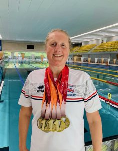 Jodie stands at the edge of a swimming pool, proudly wearing five gold medals.