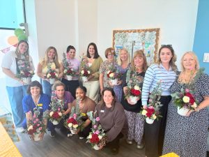 A group of midwives stand together holding flower arrangements