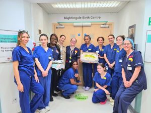 A group of midwives are gathered round a cake at King's College Hospital