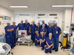 A surgical team stand round a perfusion machine in an operating theatre