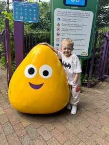 Harry, post transplant, stand smiling next to a Cbeebies character